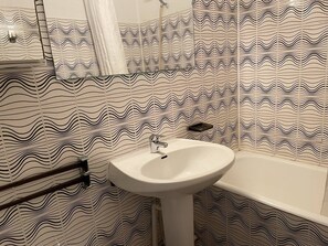 Ein Badezimmer mit Waschbecken und Badewanne, mit einem wellenförmigen Muster gefliest.