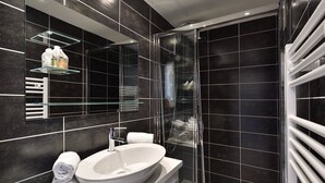 A modern bathroom with a glass-enclosed shower, a white sink, and a glass shelf with toiletries. - GLOSSY - Studio Héliopolis AB325 - Luxury -2 people (AGDE)
