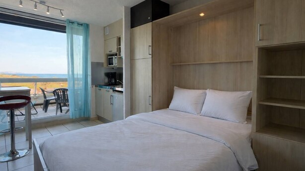Un dormitorio con cama, escritorio y vista al mar.