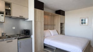 Habitación compacta con kitchenette, cama y almacenamiento integrado.