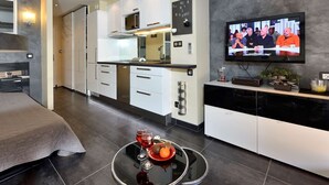 Ein modernes Hotelzimmer mit Bett, Essbereich, Küche und Fernseher.