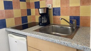 Une cuisine équipée d’un évier en acier inoxydable, d’une machine à café et d’un lave-vaisselle.