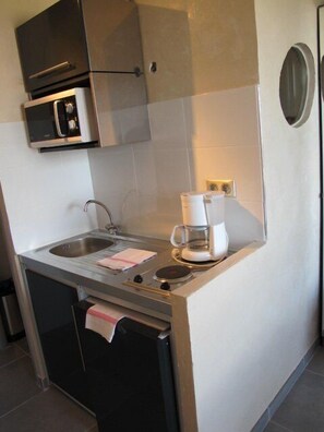 A compact kitchenette with a built-in microwave, a coffee maker, and a sink. - Studio Héliopolis AB414 - 2 people (AGDE)