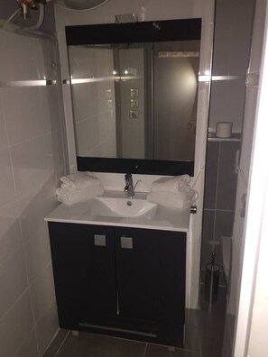 A modern bathroom with a white sink, dark cabinets, and a large mirror above the sink. - Studio Héliopolis AB414 - 2 people (AGDE)