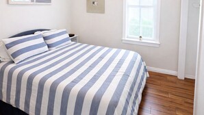 A bedroom with a bed, a ceiling fan, a window, and a door.