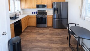 A kitchen with wooden cabinets, a stainless steel refrigerator, a microwave, an oven, and a ceiling fan.