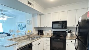 A modern kitchen with white cabinets, a black refrigerator, a microwave, and a dishwasher. - Myrtle Beach Pelican's Watch Shore Drive Condo (Myrtle Beach)