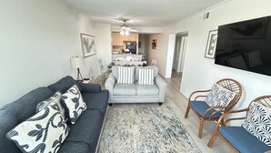 A living room with a sofa, armchairs, a rug, and a TV. - Myrtle Beach Pelican's Watch Shore Drive Condo (Myrtle Beach)