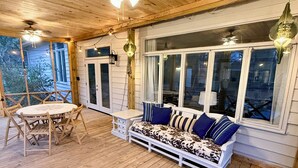 Eine Holzterrasse mit einer Couch, einem Tisch, Stühlen und einem Deckenventilator.