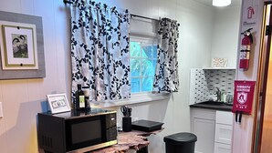 A kitchen with a wooden countertop, a microwave, a sink, and a fire extinguisher. - Nene Cottage on Pali'uli Estate by an active Volcano (Volcano)