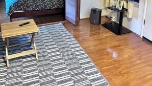 A bedroom with a bed, a television, a small table, and a remote control. - Nene Cottage on Pali'uli Estate by an active Volcano (Volcano)