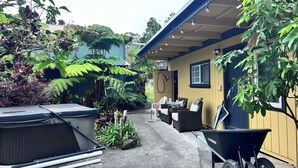 A covered outdoor area with a dining set, a wheelbarrow, and various plants. - Nene Cottage on Pali'uli Estate by an active Volcano (Volcano)