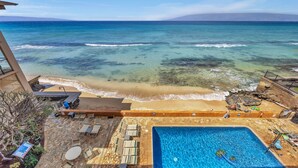 Zona de piscina con vistas al océano, una playa y sillas de descanso.