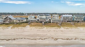 Een strandhuis met meerdere woningen, waarvan sommige balkons hebben en houten looppaden naar het strand.