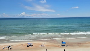 Una spiaggia con cielo sereno, acque calme e persone che praticano diverse attività.