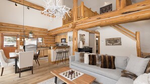 Interno di una baita in legno con zona pranzo, cucina e soggiorno.