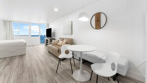 A modern living room with a sofa, a round table, and a TV. - Modern Beachfront Studio - Ocean View - Free Beach Chairs (Panama City Beach)