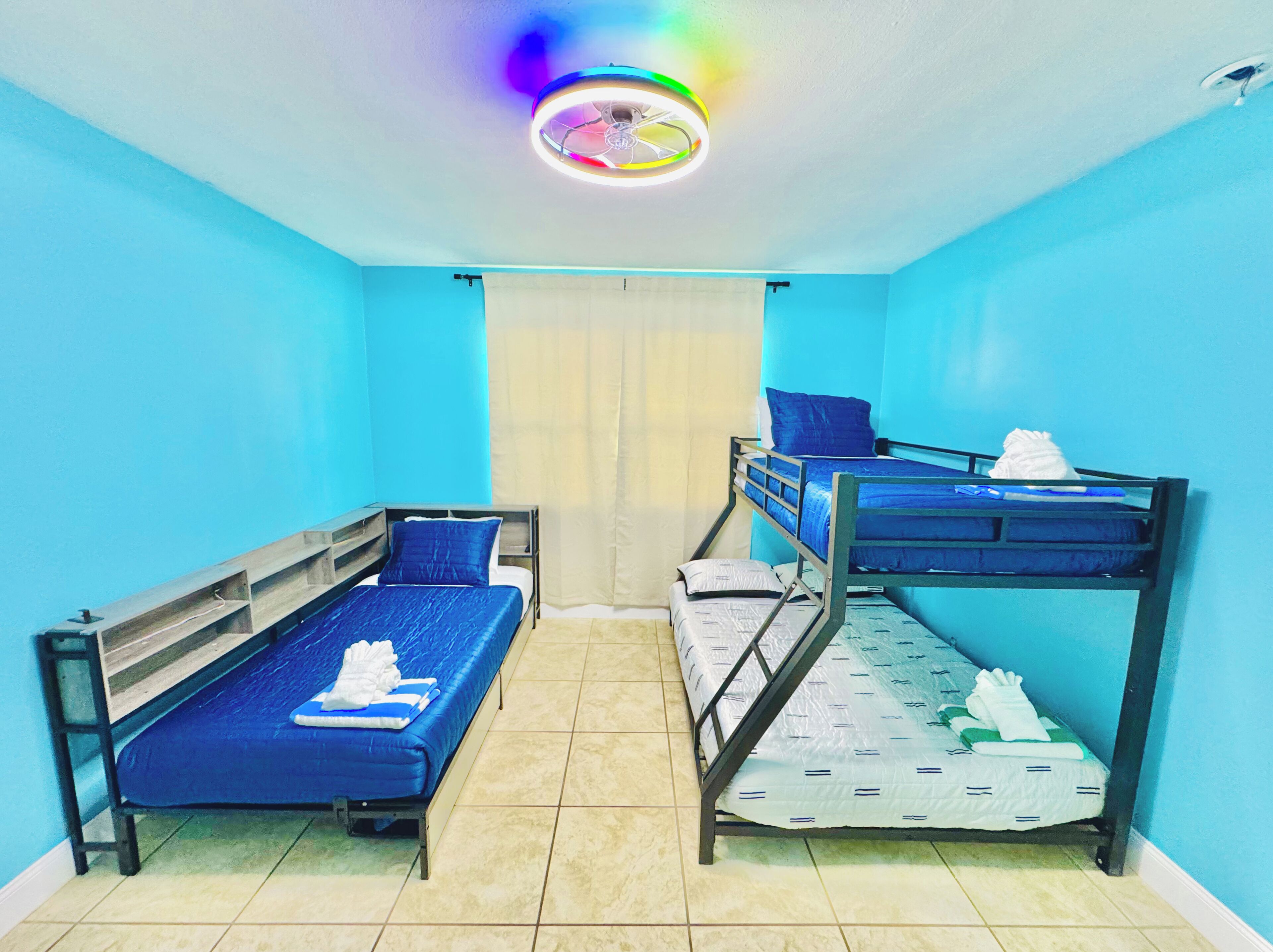 A room with two bunk beds, a ceiling fan, and a window with curtains.
