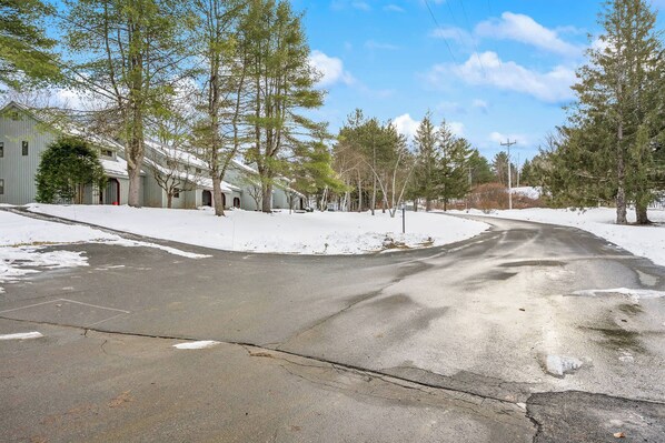 A snow-covered street with a building on the left. - End-Unit + Golf Course Views | Windsor Village #3E (Quechee)