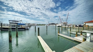 A marina with docked boats, wooden piers, and a clear sky. - The Blue Pelican by Avantstay Pirates Bay Retreat + 2 Shared Lagoon Pools 3 Blocks to Beach (Port Aransas)