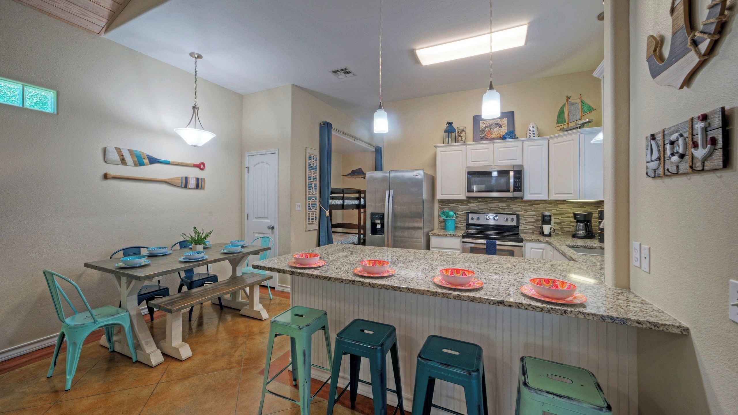A kitchen with a central island, a dining table with chairs, and a refrigerator.