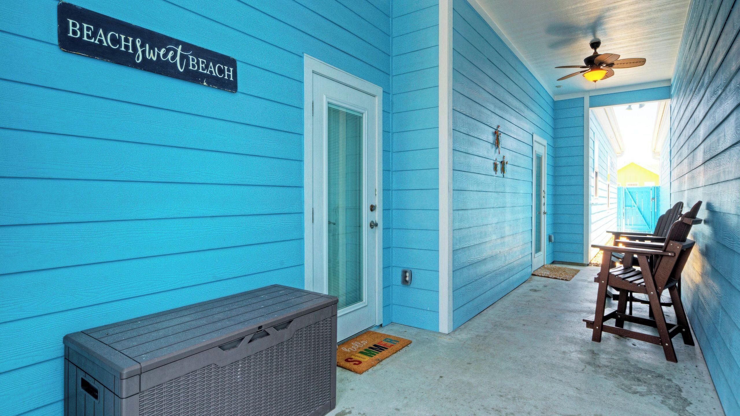 A blue exterior with a door, a bench, and a fan.