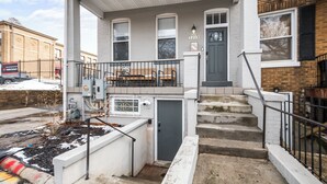 Ein zweistöckiges Haus mit einer Veranda, einer kleinen Bank und einer Tür, auf der die Nummer 1213 steht.