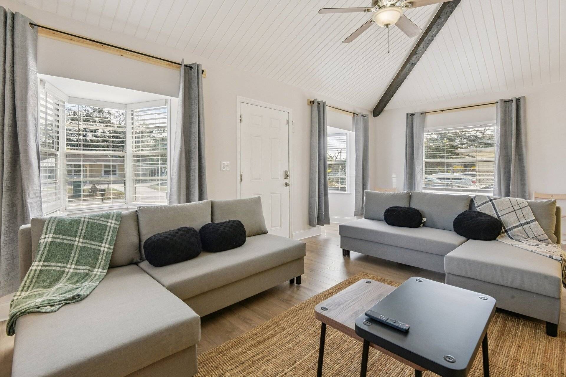 A modern living room with two sofas, a coffee table, and a ceiling fan.