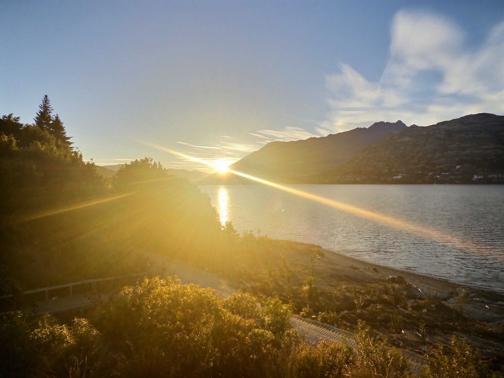 A sunset over a lake with mountains in the background.