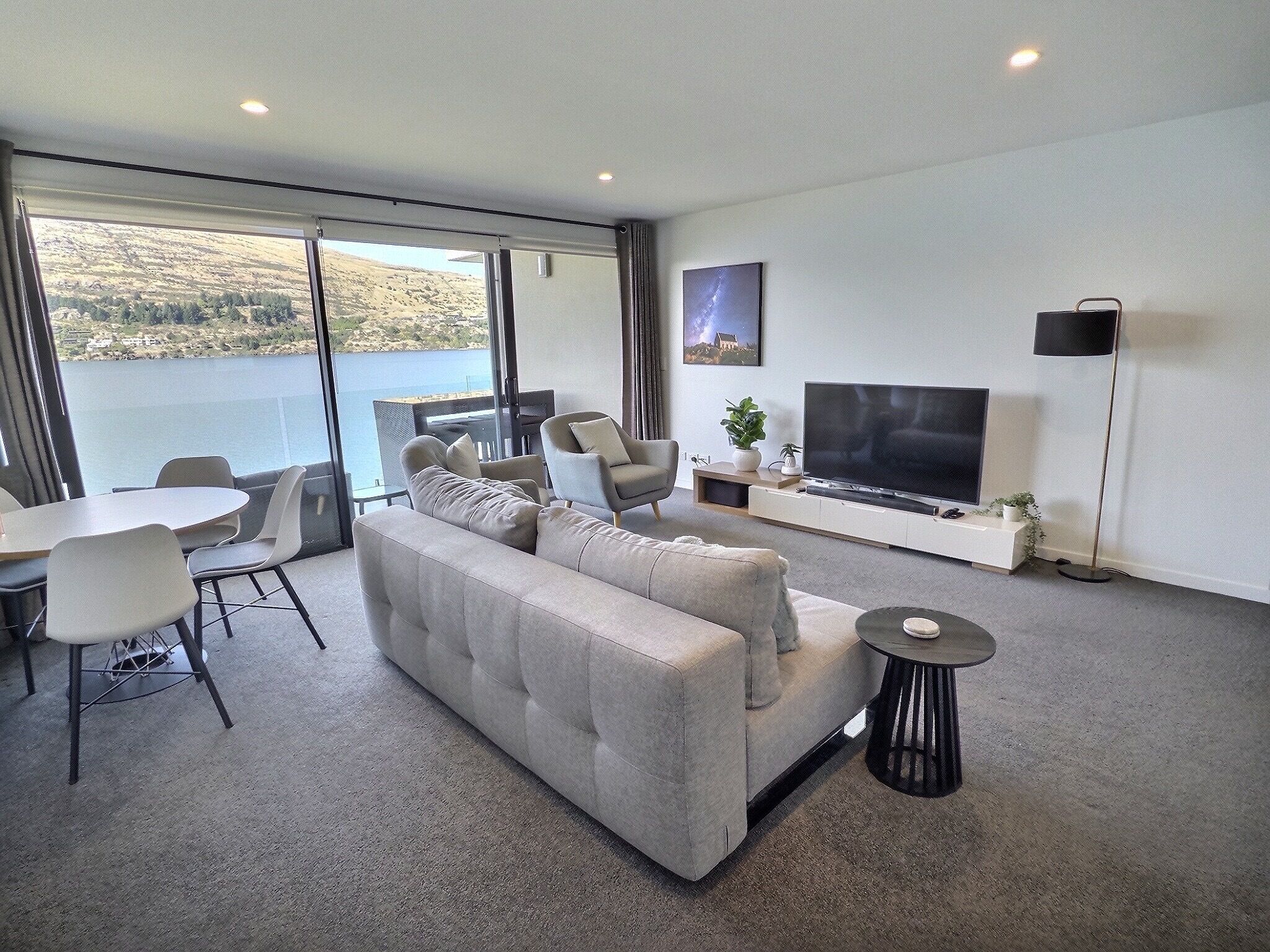 A modern living room with a sofa, TV, and dining area.
