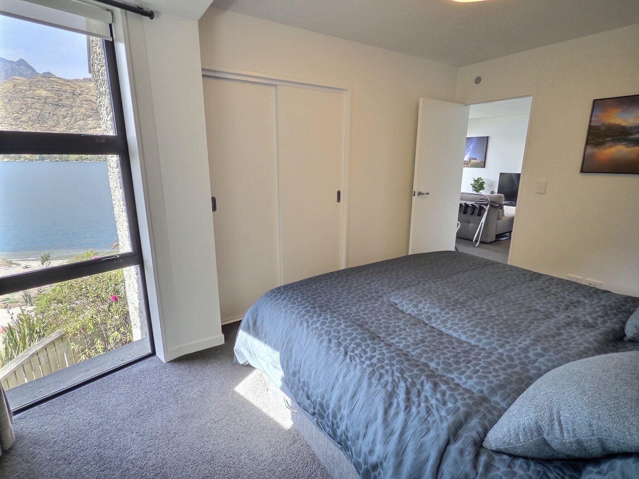 Ein Schlafzimmer mit einem großen Bett, einer Schiebetür zum Balkon und Blick auf eine Berglandschaft.