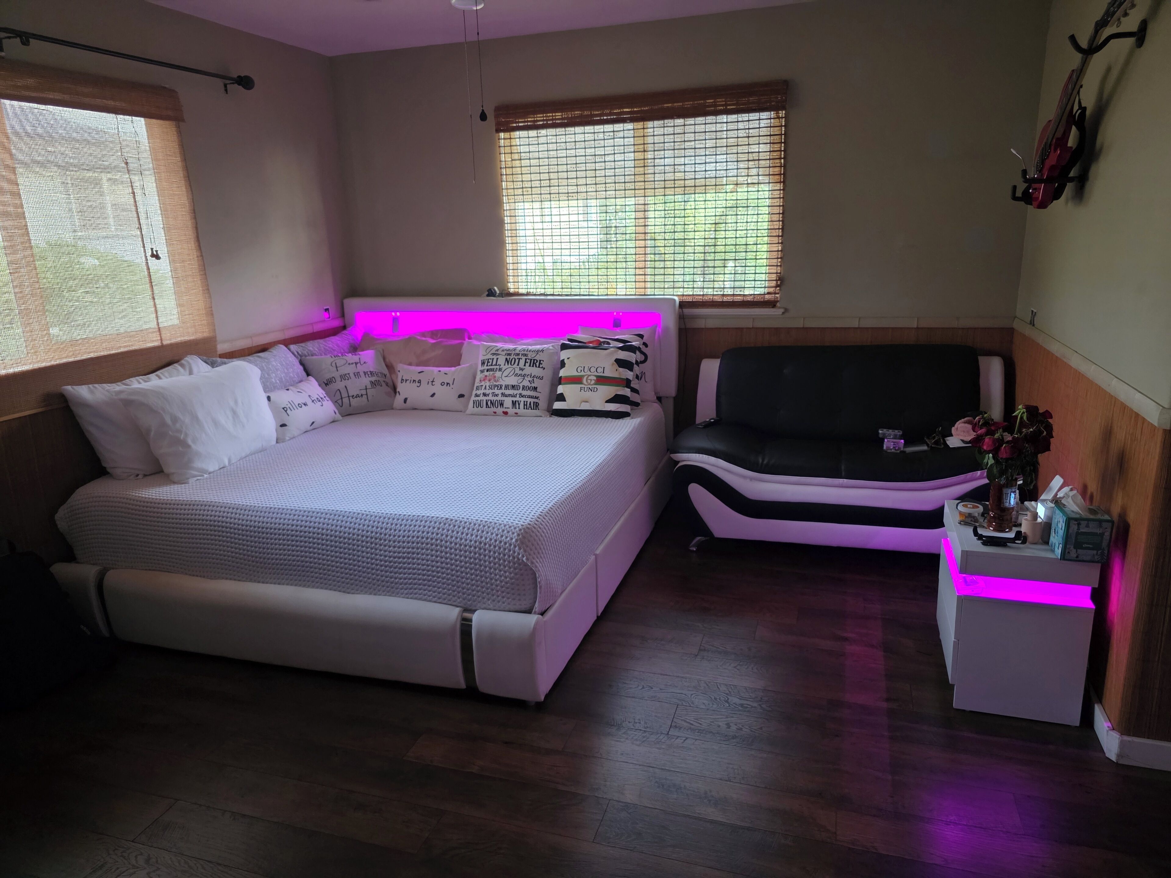 Een slaapkamer met een bed, een sofa, een klein tafeltje en een raam met zonwering.