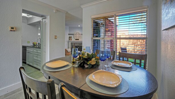 A dining area with a wooden table, chairs, and a window with blinds.