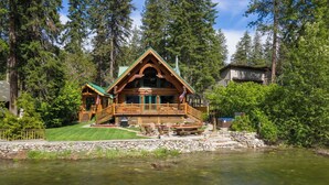 A cabin with a wooden exterior, a porch, and a view of a river. - Riverfront Log cabin, sleeps 6 guests with hot tub (Leavenworth)