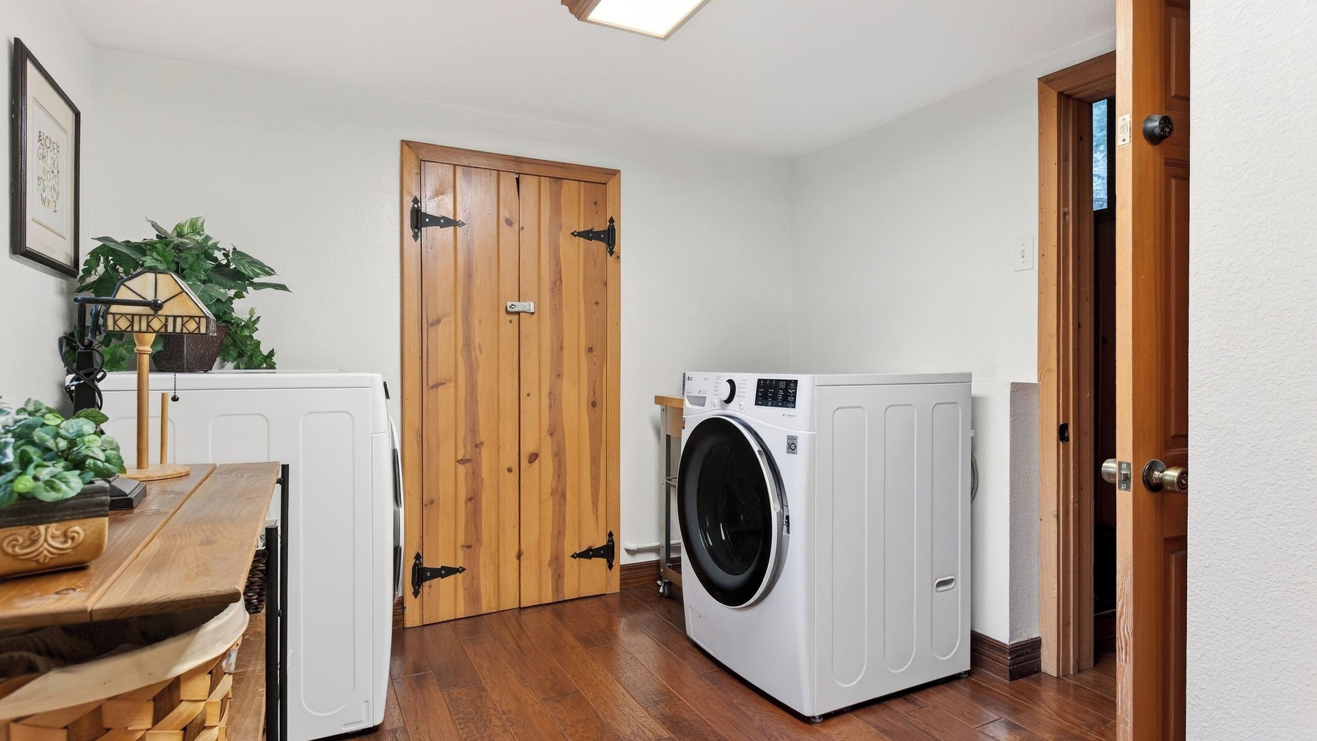 A laundry room with a washing machine, dryer, and wooden door.