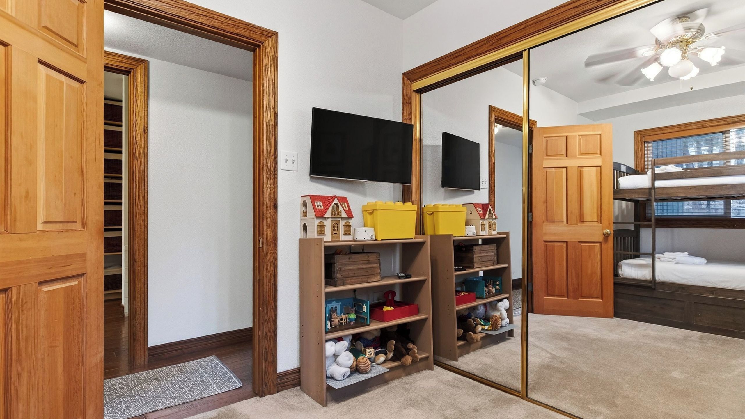 Una habitación con un armario de madera, un espejo, un televisor y una cama litera.