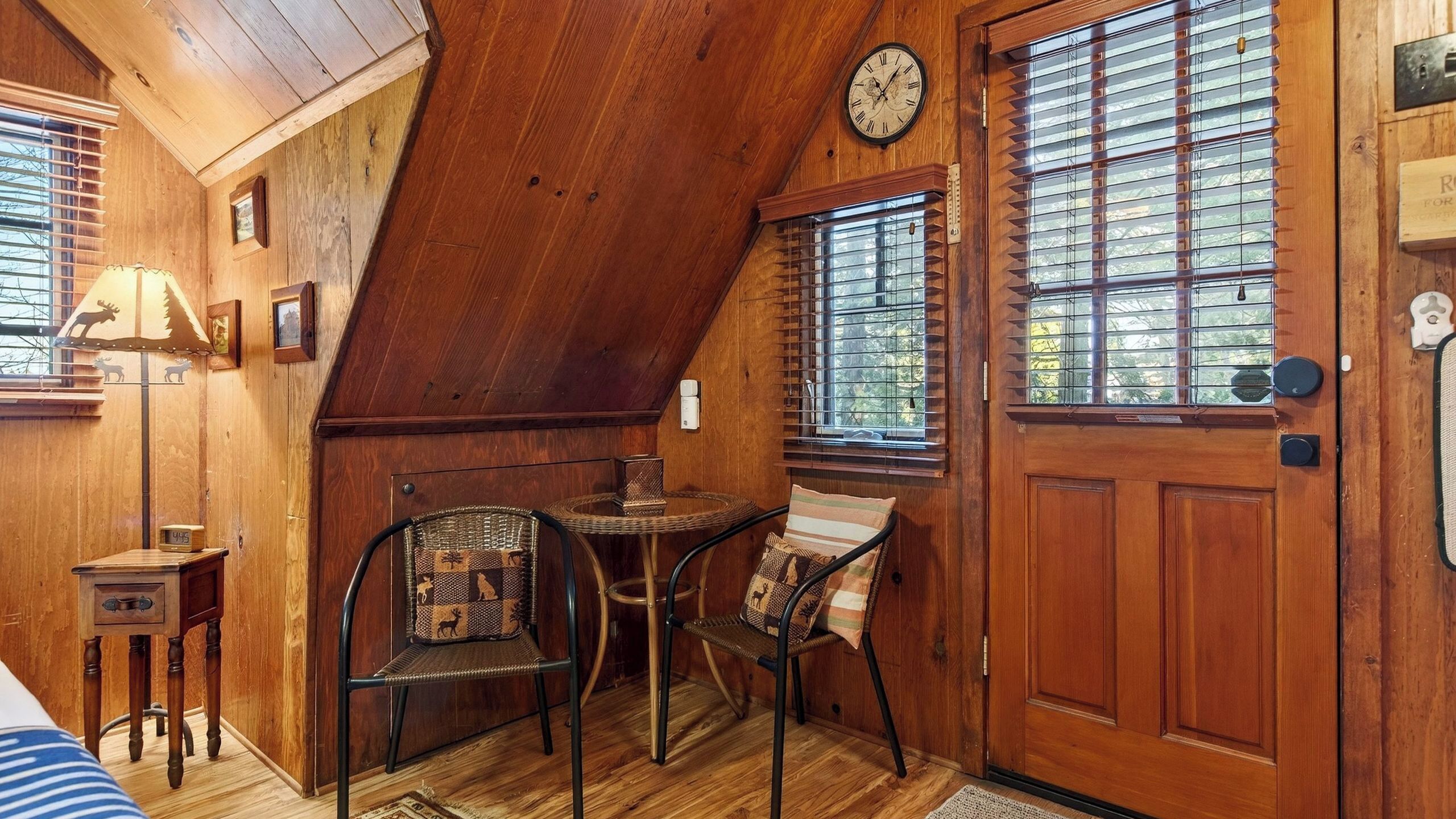 A cozy, wooden interior with a dining area, a clock, and a door with a nameplate.