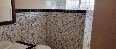 A bathroom with a mosaic tile wall, a toilet, and a sink.