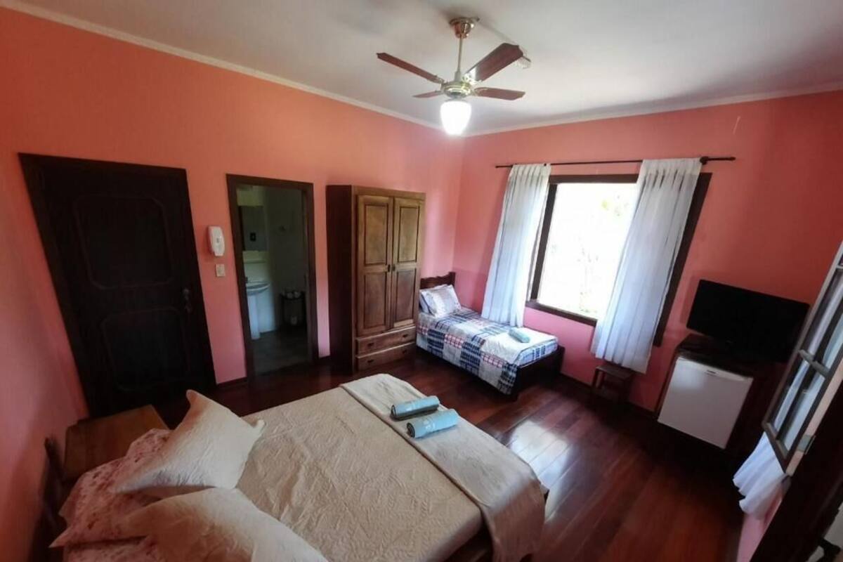 Une chambre à coucher avec un lit, une armoire, une télévision et une fenêtre avec des rideaux.