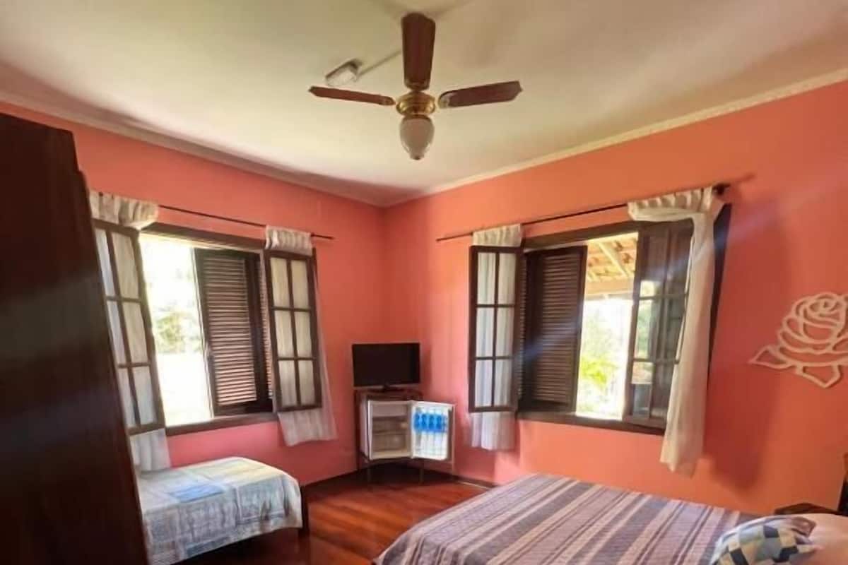 Une chambre avec deux lits, un ventilateur de plafond et une télévision.