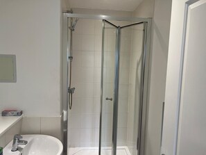 Une salle de bain moderne avec une douche à parois de verre, un lavabo blanc et un miroir au mur.
