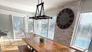 A dining area with a wooden table, benches, a hanging light fixture, and a wall clock. - CASABELLA,4bed/2bath, 8 min from beach/ w/ POOL (Fort Walton Beach)