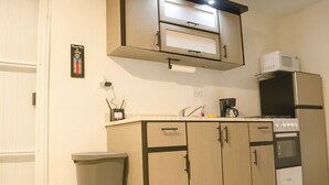 A compact kitchen with a microwave, stove, and sink. - Mami's LITTLE Corner - Near Airport, Beaches and Malls (San Juan)