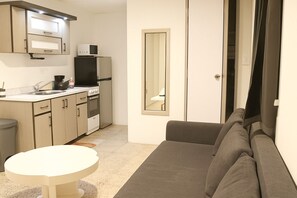 Ett kompakt bostadsutrymme med ett litet kök, en soffa och ett litet bord.