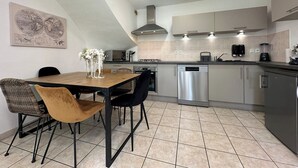 Une cuisine moderne avec un coin repas, comprenant une table en bois, des chaises et un lave-vaisselle en acier inoxydable.