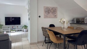 Un salon moderne doté d’un téléviseur à écran plat, d’une table à manger avec des chaises, d’un coin cuisine avec un four à micro-ondes et d’une grande œuvre d’art représentant une carte du monde accrochée au mur.