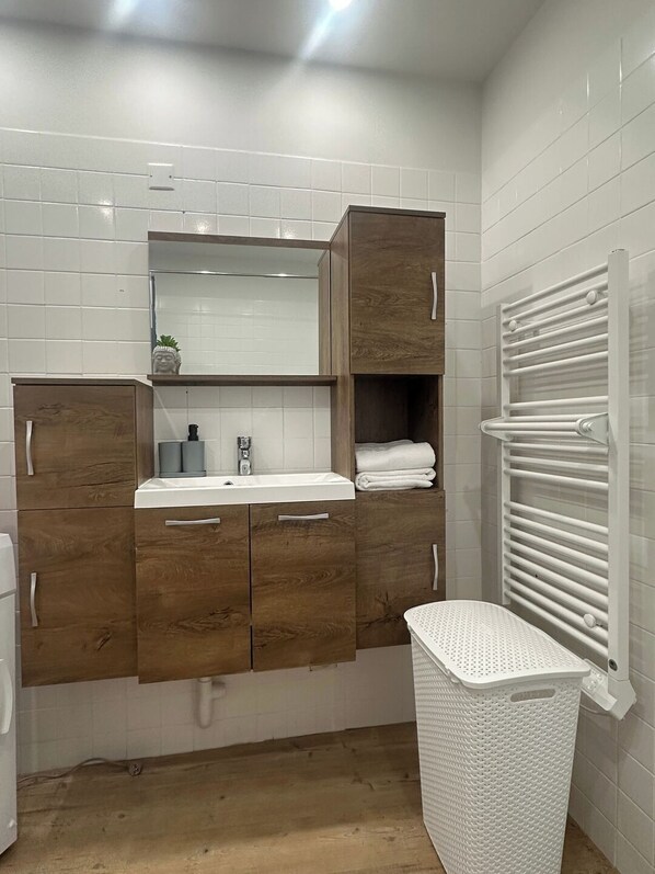 Un baño con tocador de madera, un lavabo blanco, un espejo y un perchero para toallas.