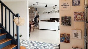 Un escalier menant à un espace de vie doté d’un sol à motifs, une cuisine à l’arrière-plan et divers éléments décoratifs sur les murs.