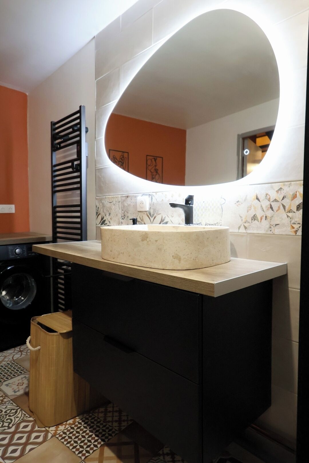 A bathroom with a round mirror, a sink, and a washing machine.