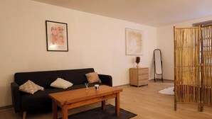 Una sala moderna con un sofá negro, una mesa de centro de madera y un separador decorativo.